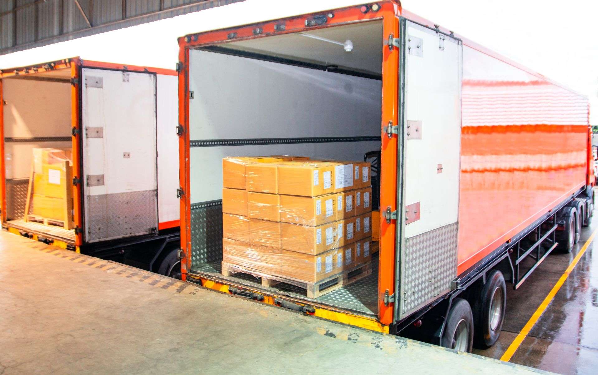 Cargo truck with orange accents unloading pallets of packaged goods, related to logistics and FF&E services in Jacksonville by Skinner Moving & Storage.