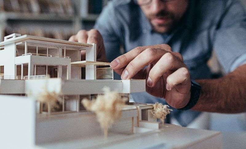Man adjusting architectural model, highlighting precision in design, relevant to Jacksonville white glove delivery services for architects by Skinner Moving & Storage.