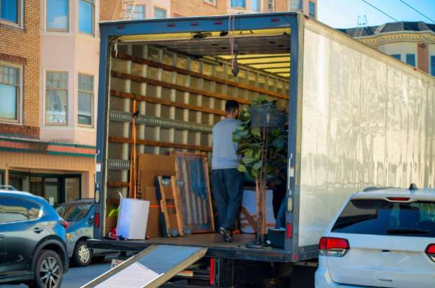 Professional moving crew unloading furniture from truck in urban setting, showcasing Jacksonville white glove delivery services for high-value items.