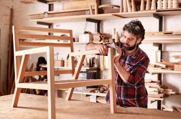 Craftsman assembling wooden chair in workshop, showcasing furniture manufacturing process relevant to Jacksonville white glove delivery services.