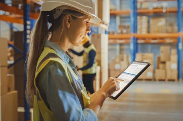 Warehouse employee using tablet for inventory management in climate-controlled storage facility.