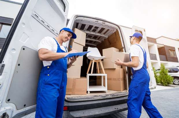 Two movers in blue uniforms handling furniture and boxes in a delivery van, emphasizing white glove delivery services for valuable items in Jacksonville.
