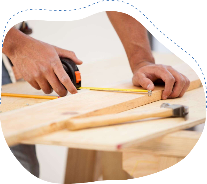 Hands measuring a wooden plank with a tape measure and pencil, surrounded by tools like a hammer, illustrating packing and preparation for moving services in Florida.
