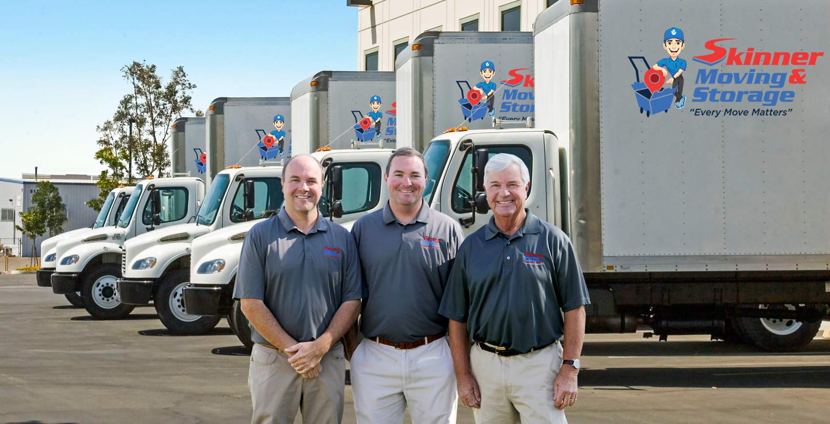 Three Skinner Moving & Storage owners standing in front of their fleet of branded moving trucks in a company lot