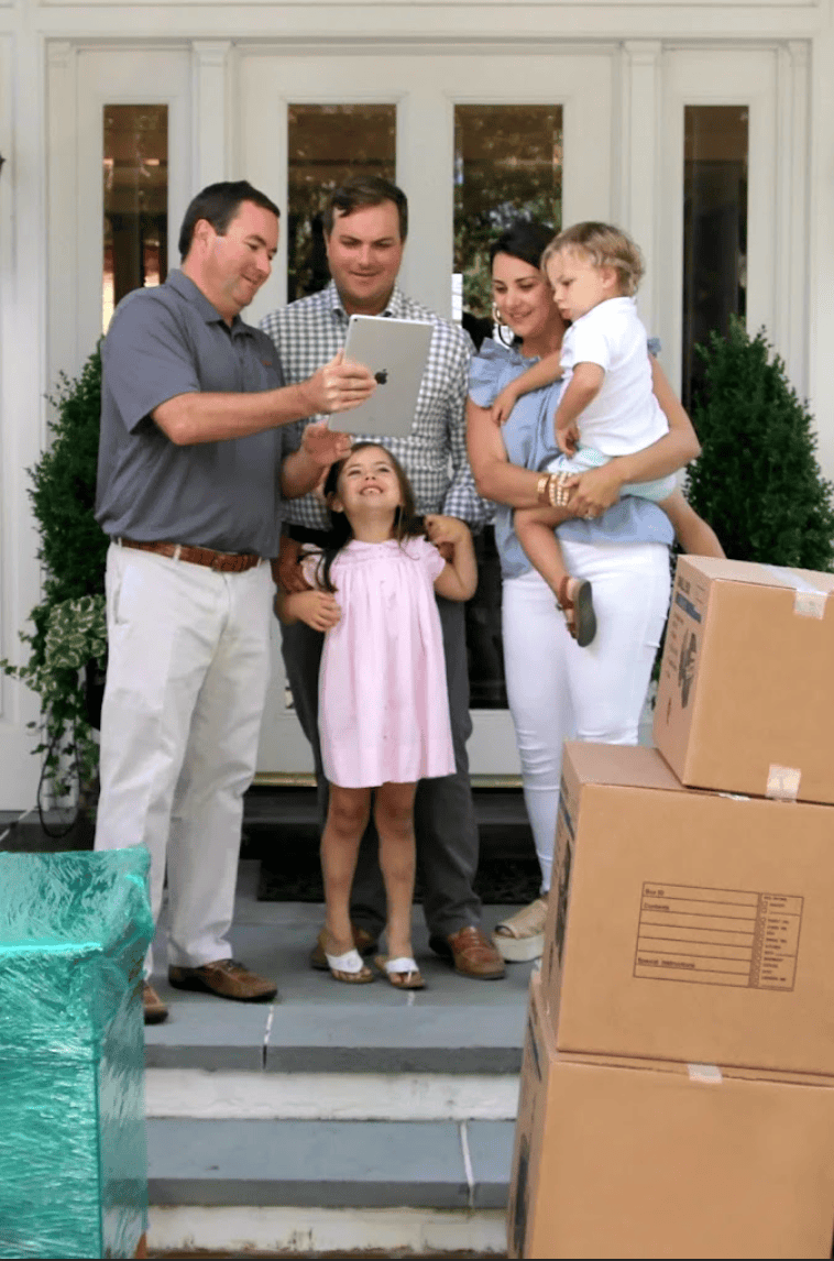 A Skinner Moving & Storage representative showing a tablet to a family with two young children outside their home during a moving consultation